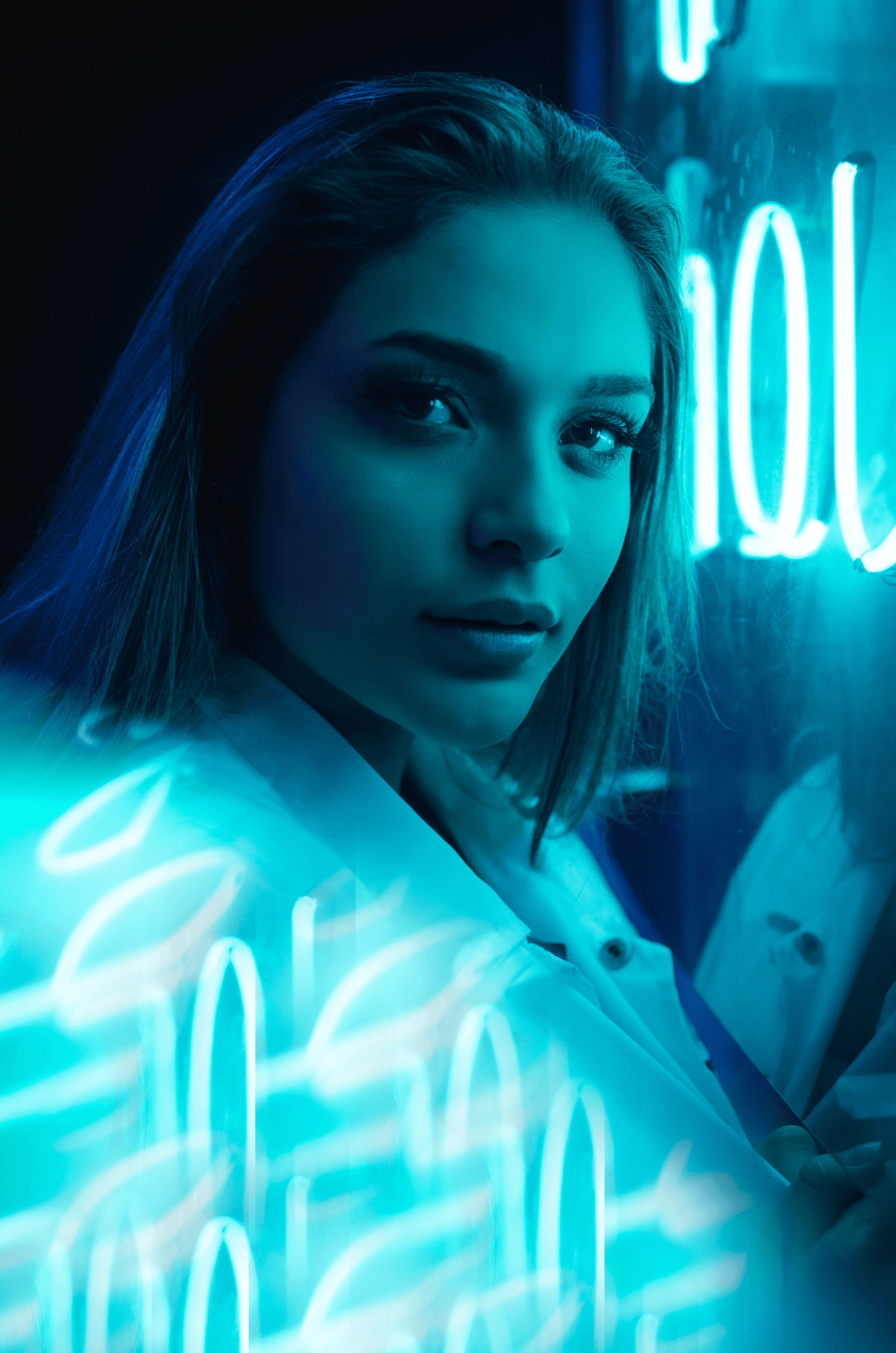 Close-up portrait lit by pink and blue neon signage