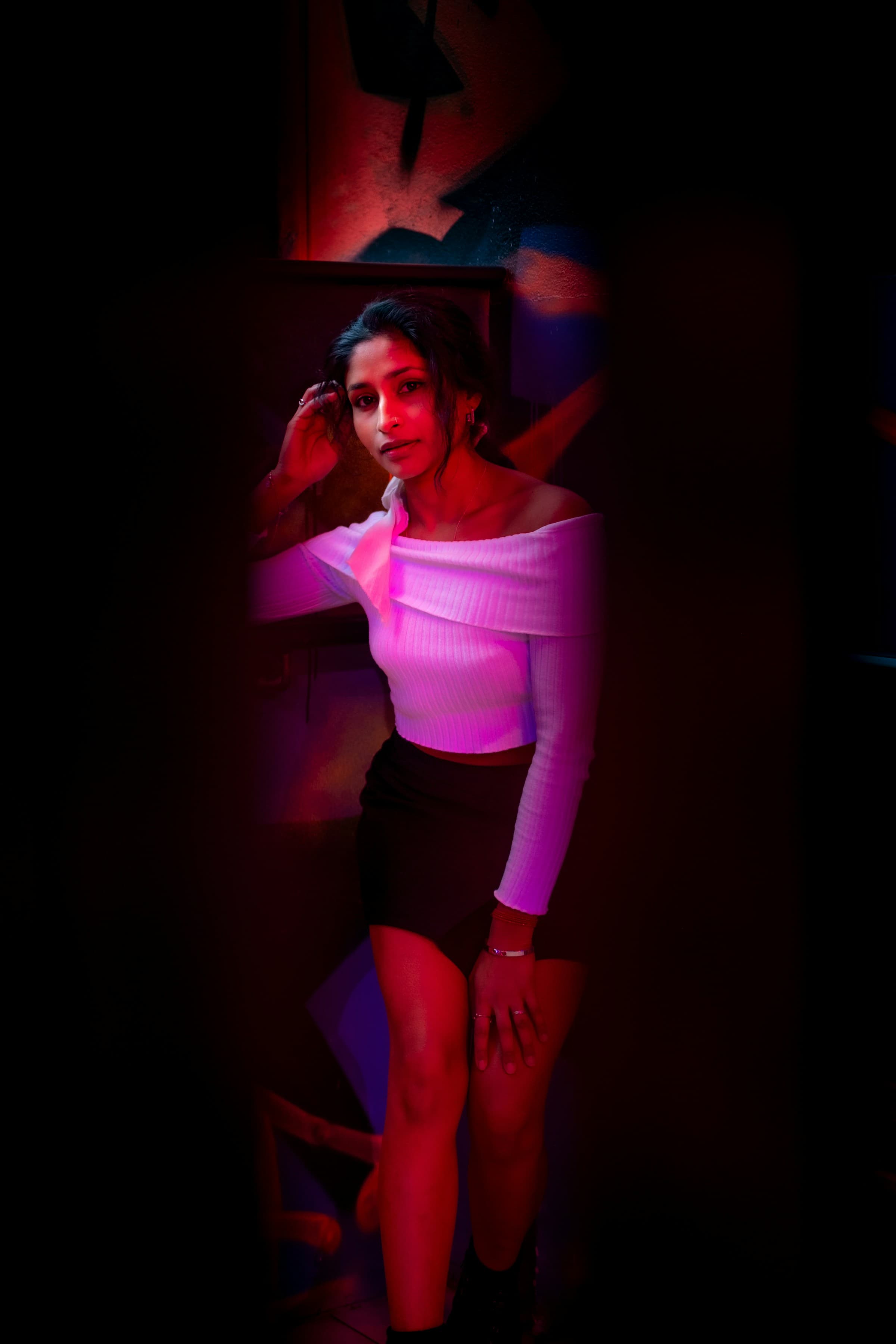 Portrait in an off-the-shoulder top, lit by red light