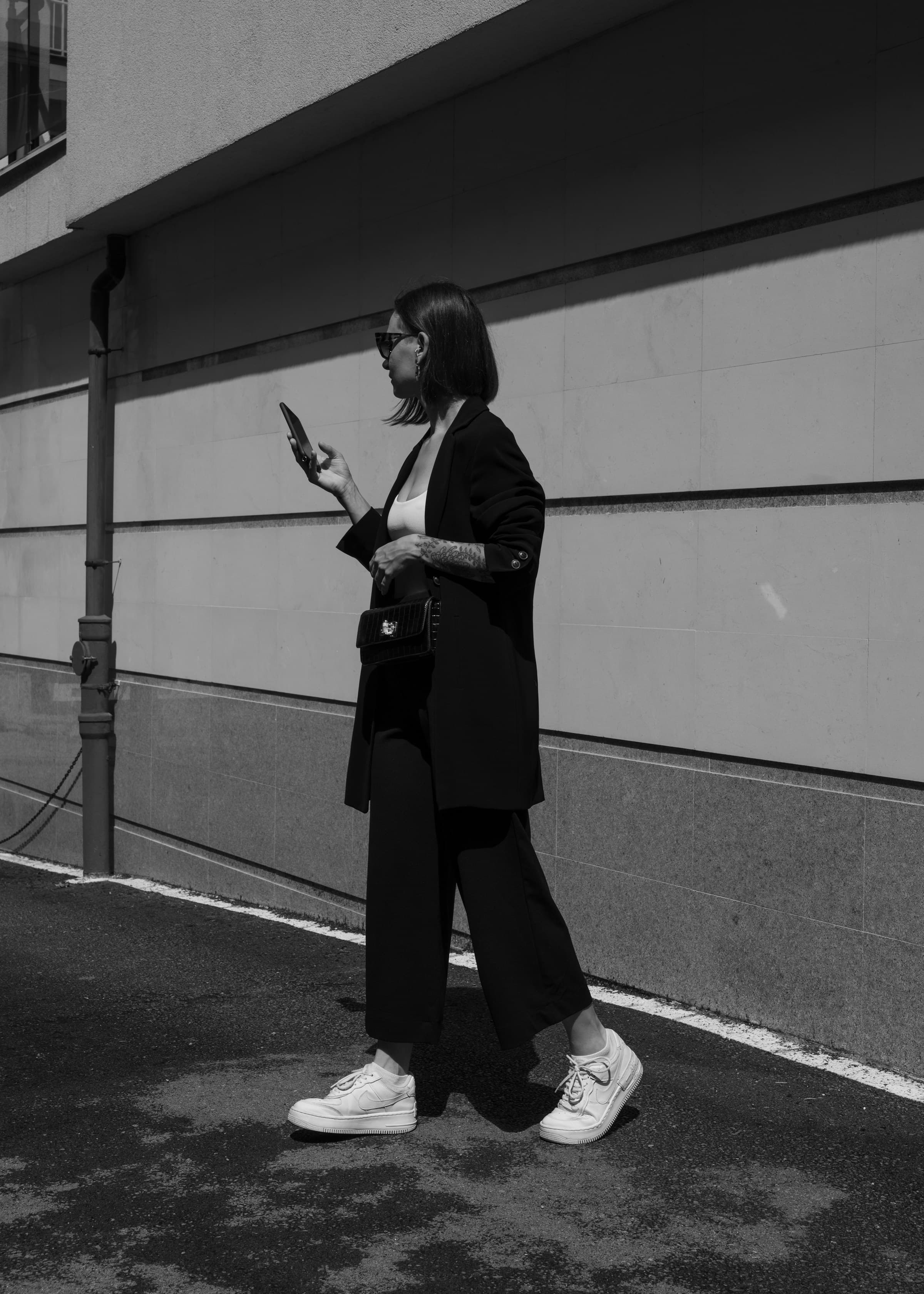 Street-style frame of a woman walking while holding a phone