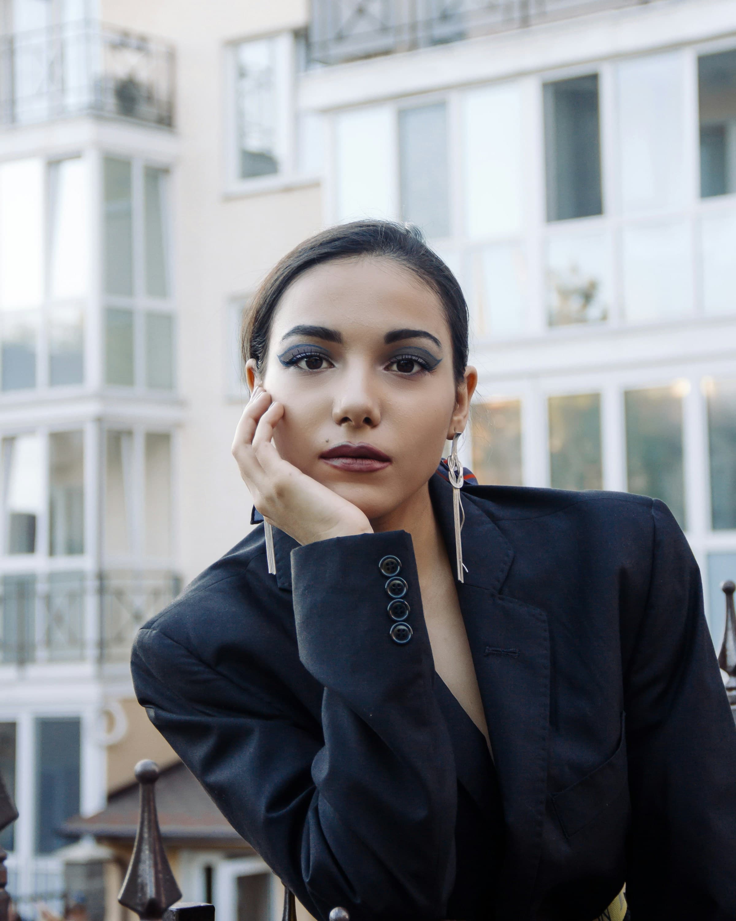 Editorial portrait of a woman in a tailored black blazer, hands framing her face